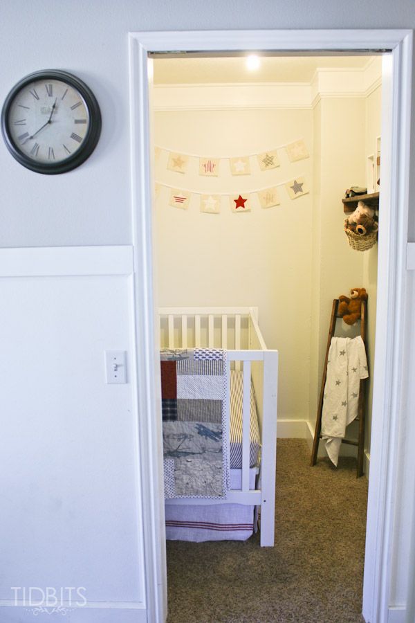 a baby's crib in the corner of a room with a clock on the wall