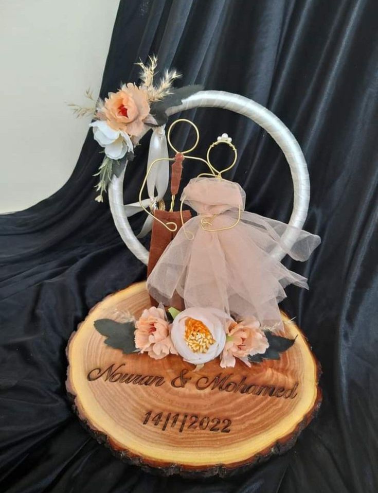 a wedding cake on top of a wooden slice with flowers and ribbon around it's edges