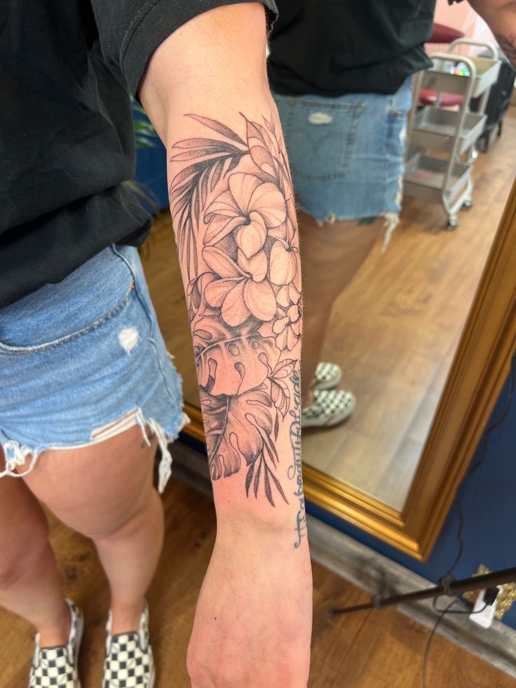 a woman's arm with flowers on it and a mirror in the back ground