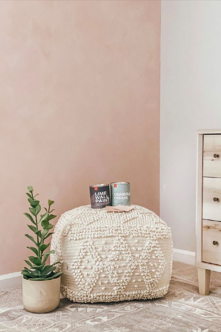 a white pouffle sitting on top of a wooden table next to a potted plant