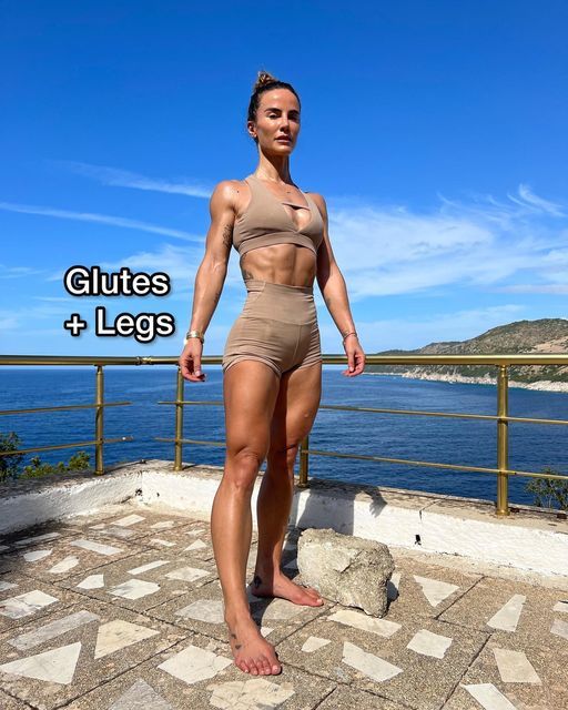 a woman standing on top of a stone floor next to the ocean