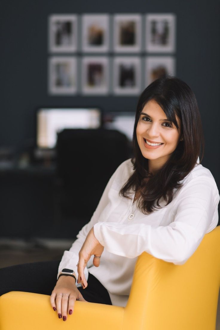 a woman sitting in a yellow chair smiling at the camera