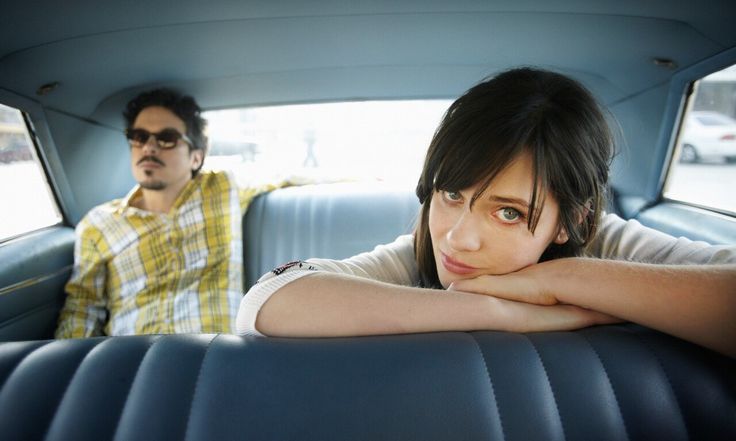 two people sitting in the back of a car with their arms folded out and looking at the camera