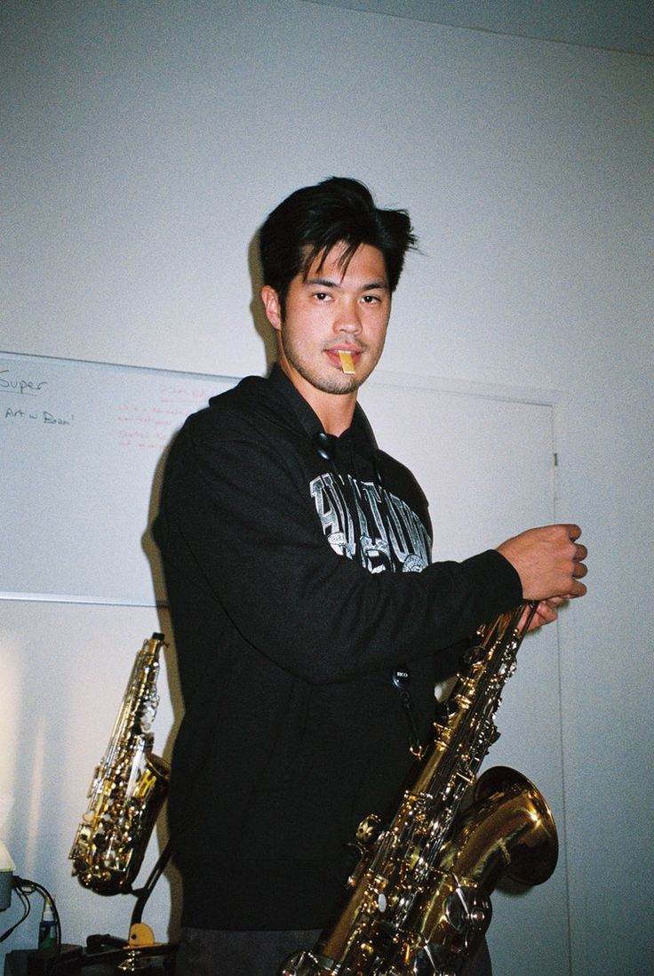 a young man is holding two saxophones in his hands