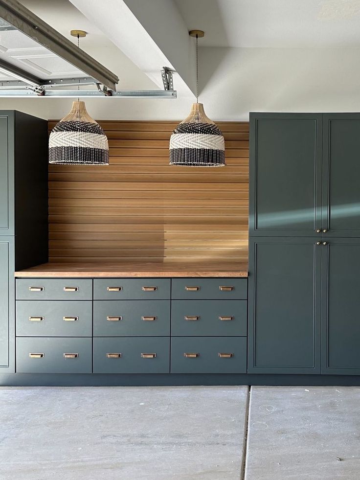 two lamps are hanging from the ceiling above some drawers in a room with blue cabinets