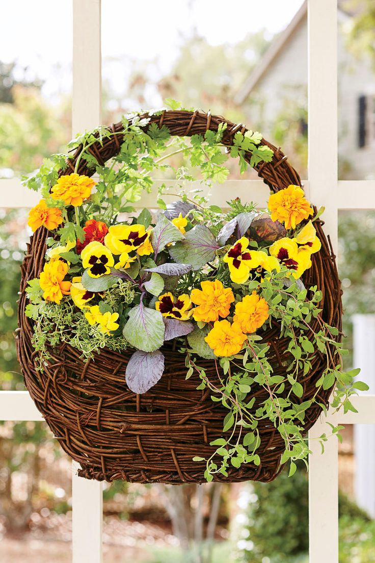 a wicker basket filled with flowers hanging from a window sill in front of a house