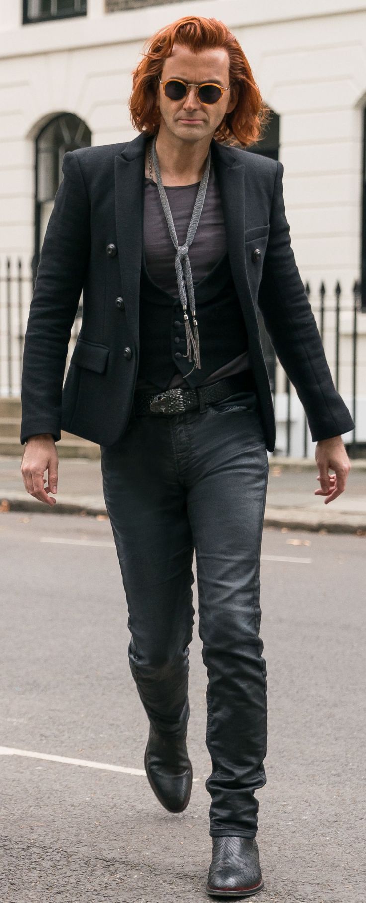 a woman with red hair is walking down the street wearing black pants and a blazer