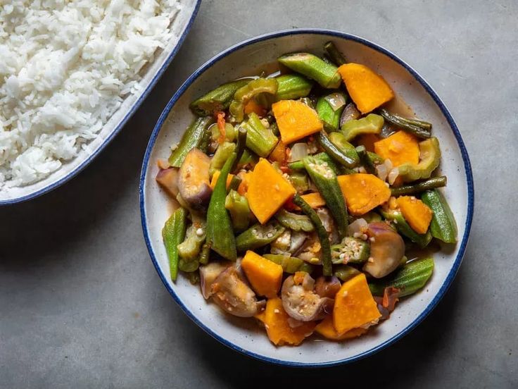 a bowl filled with rice and veggies next to another bowl full of food