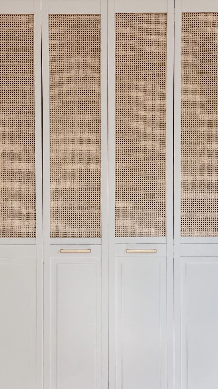 an empty room with white walls and wicker panels on the doors, in front of a bench