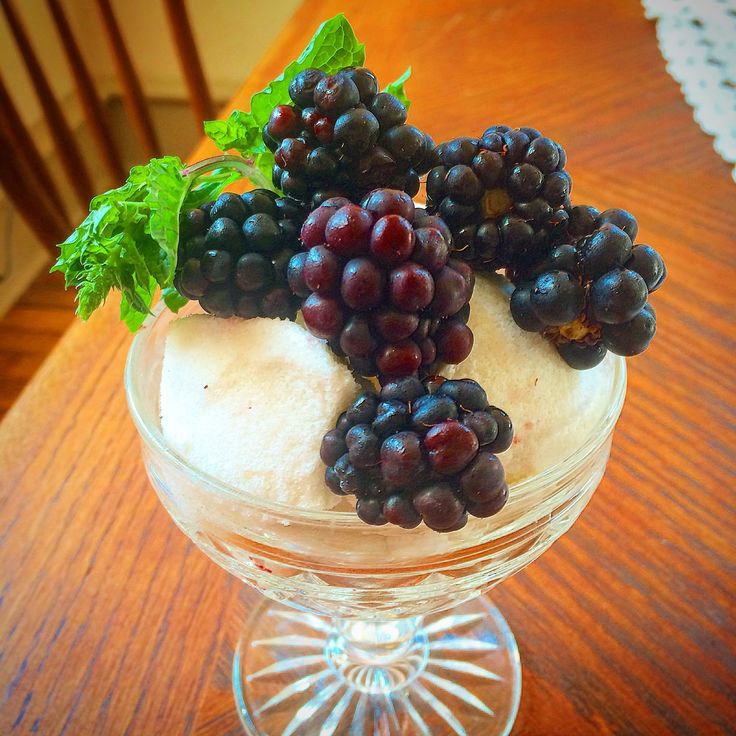 grapes are arranged on top of ice cream in a glass bowl with mint sprigs