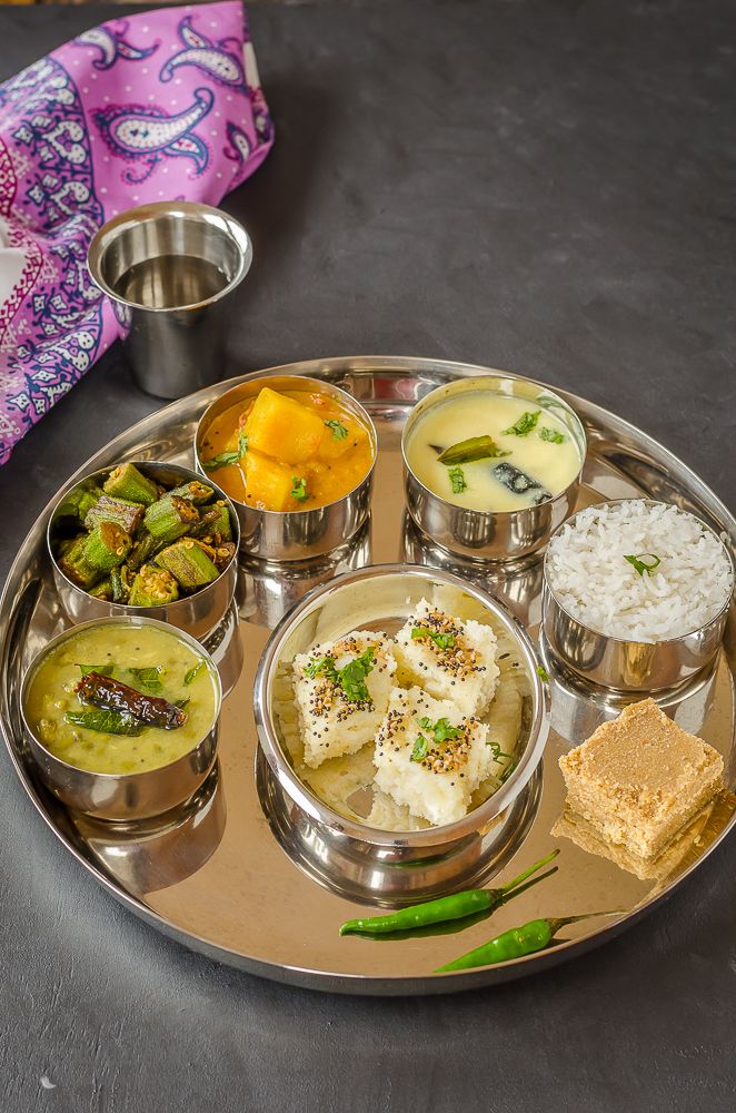 a silver plate topped with different types of food on top of a metal tray next to other dishes