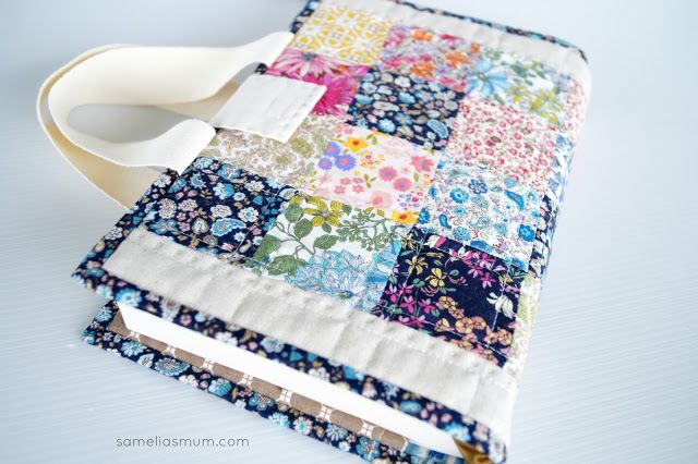 a close up of a book covered in patchwork fabric with a pair of scissors