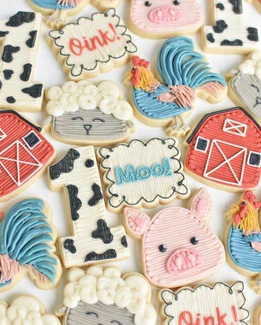 decorated cookies with farm animals and words are on a white tablecloth that is laid out