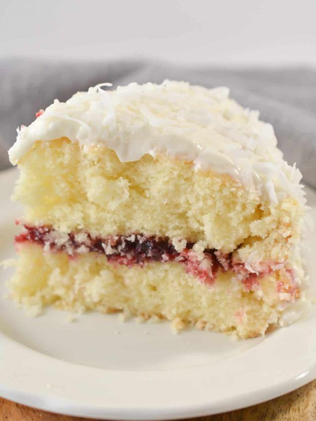 a piece of cake on a plate with white frosting and cranberry filling