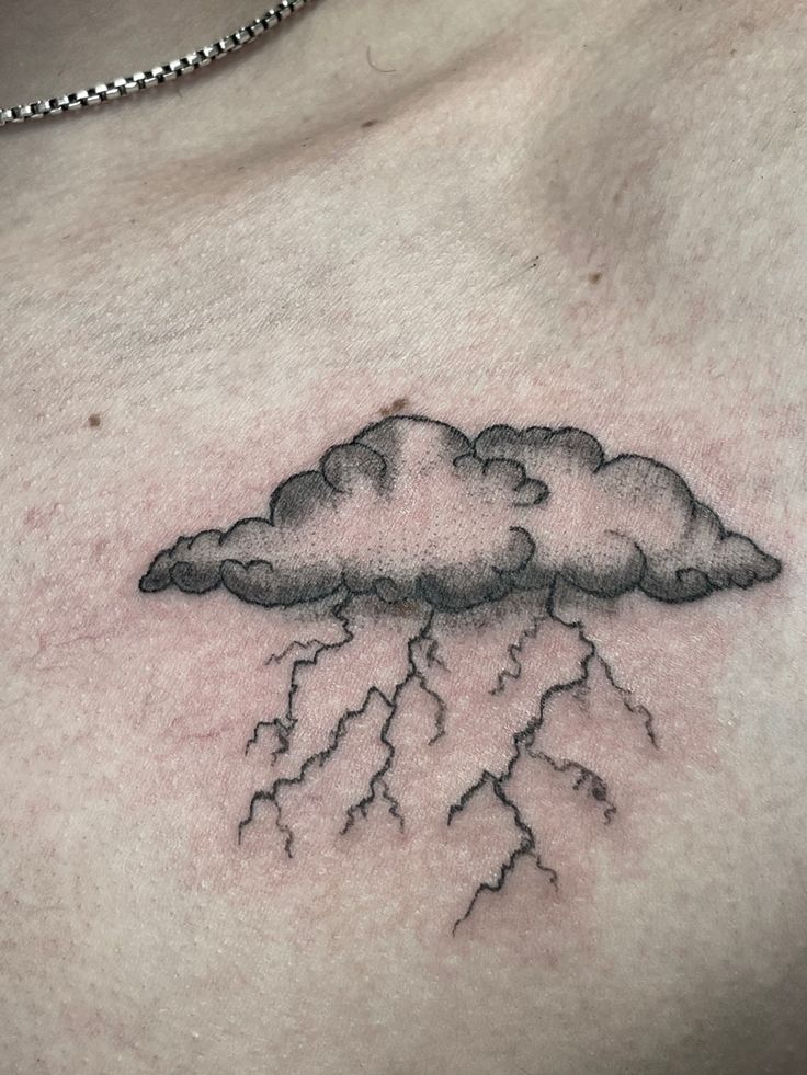 a man's chest with a cloud and lightning tattoo on it