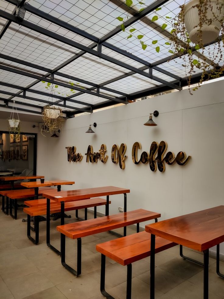 the inside of a coffee shop with wooden benches and tables in front of it that have signs on the wall