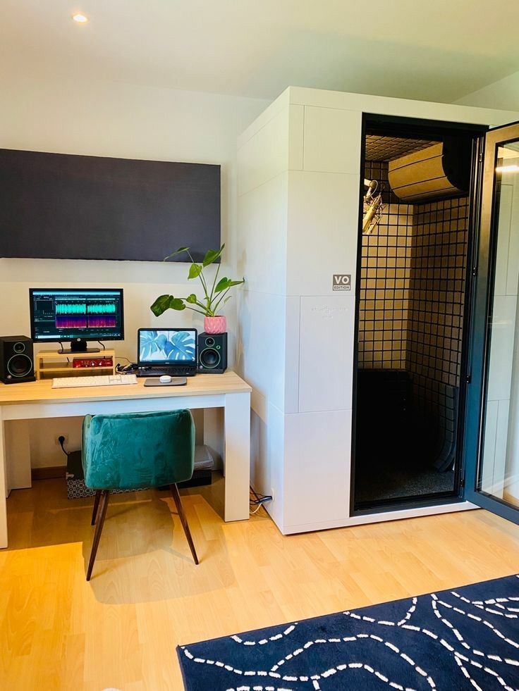 there is a desk with two computers on it and a rug in front of it