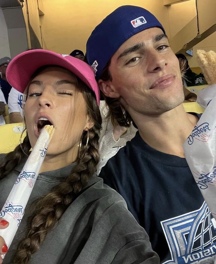 two people sitting next to each other with baseball bats in their mouths and one person holding a stuffed animal