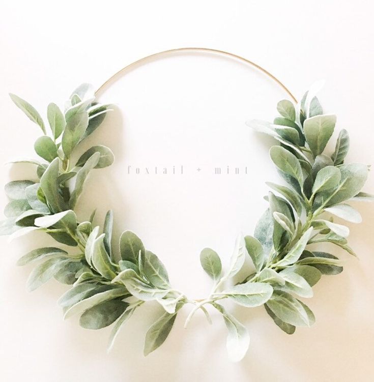 a wreath made out of green leaves on top of a white wall with the words travail mint