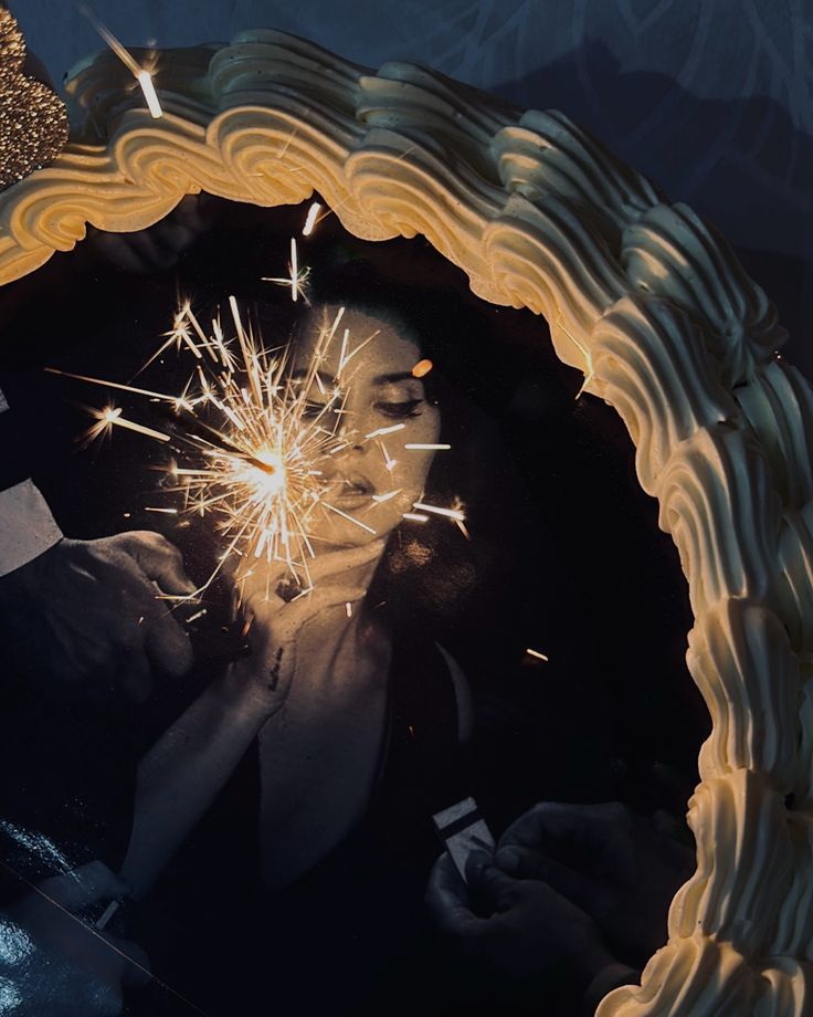 a woman holding a sparkler in her hand and looking at it through a mirror