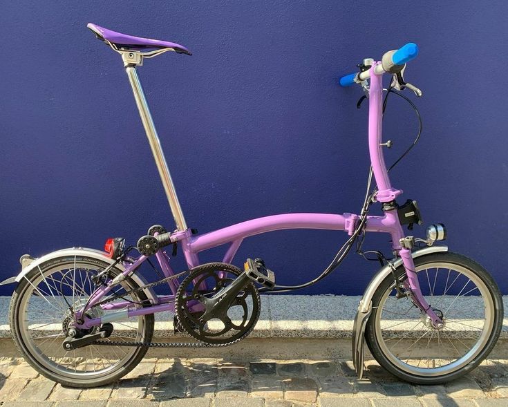 a pink bicycle parked next to a blue wall