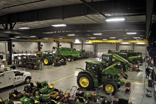 several green tractors are parked in a warehouse