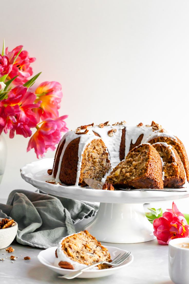 a bundt cake with white icing sitting on a plate next to some flowers