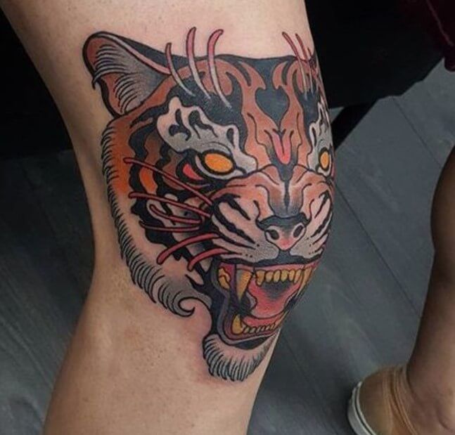 a tattoo on the leg of a person with an orange tiger head and red eyes