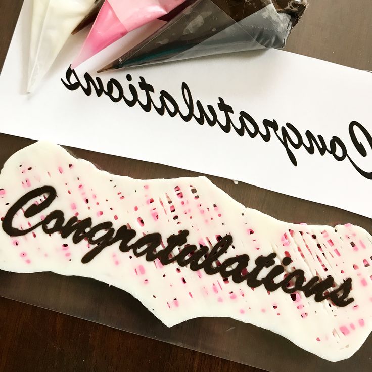 congratulations written in chocolate on top of a piece of paper next to a candy bar