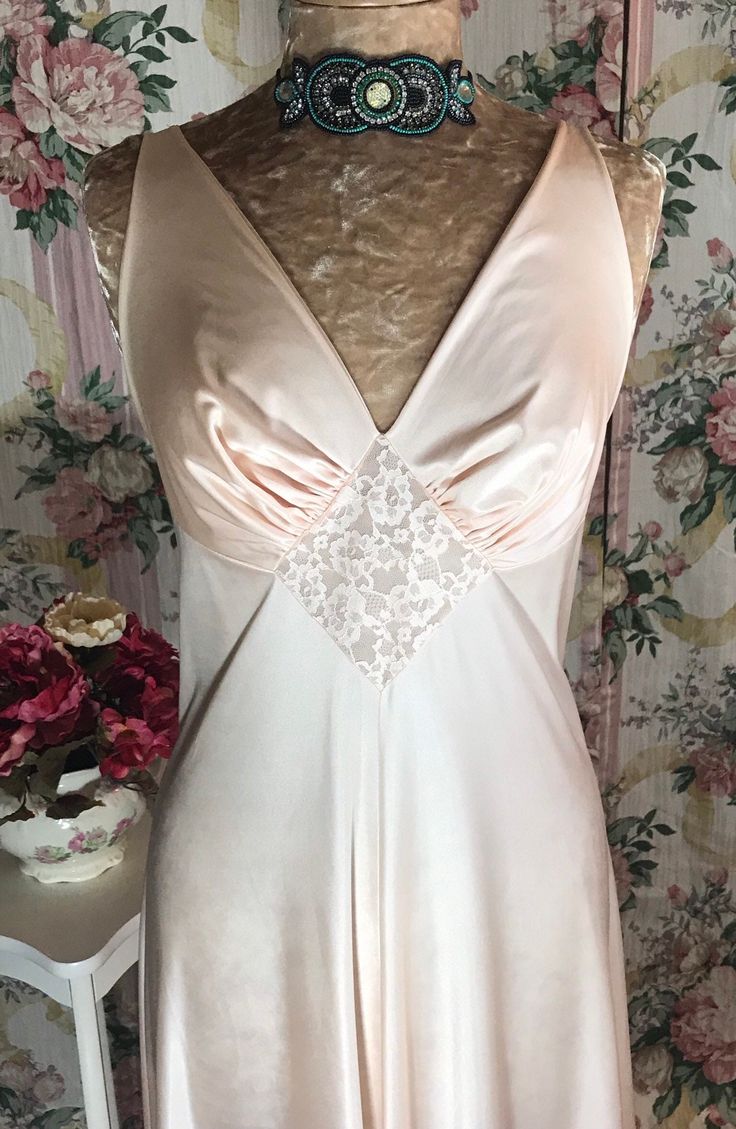 This Olga nightgown is a Powdered Apricot color in size 38(L-XL) in style #9697.  With its captivating charm this nightgown will leave anyone looking like a 1930's glamor movie star!  This is one of Olga's more simple styles, but still it has more than just clean lines, as it has a romantic appeal with just a touch of lace giving it a very chic Hollywood look.  This nightgown is not very stretchy at the bust like most Olga's so the best fit would be for anyone who wears a (L-XL). The skirt is ve Feminine Satin Nightgown For Sleep, Feminine Satin Nightgown For Bedtime, Elegant Pink Slip Dress For Bedtime, Coquette Sleeveless Nightgown For Wedding Night, Elegant V-neck Chemise For Bedtime, Feminine V-neck Chemise For Wedding Night, Satin Nightgown With Bias Cut For Sleep, Satin Bias Cut Nightgown For Sleep, Satin Coquette Nightgown For Sleep