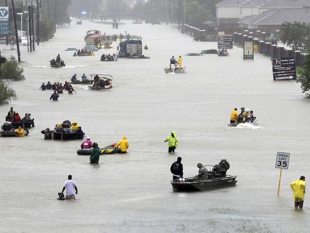 many people are riding in small boats on a flooded street