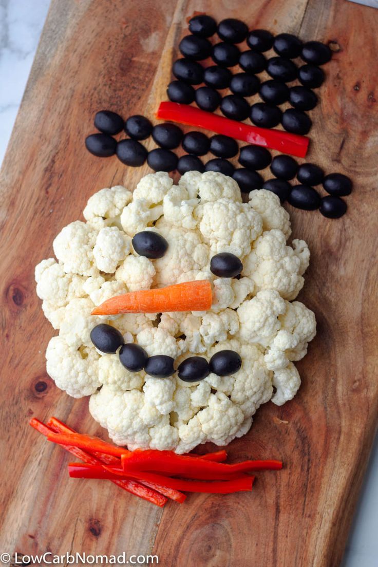 cauliflower and carrots in the shape of a snowman on a cutting board