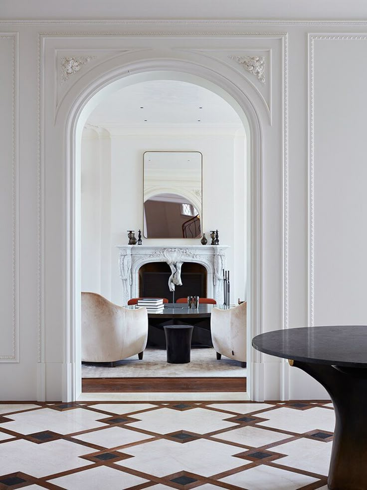 a living room with an arched doorway leading to a dining area and fireplace in the background