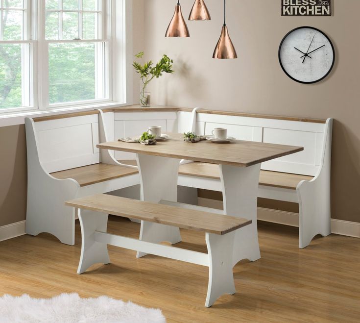 a kitchen table with benches and a clock on the wall above it, in front of a window