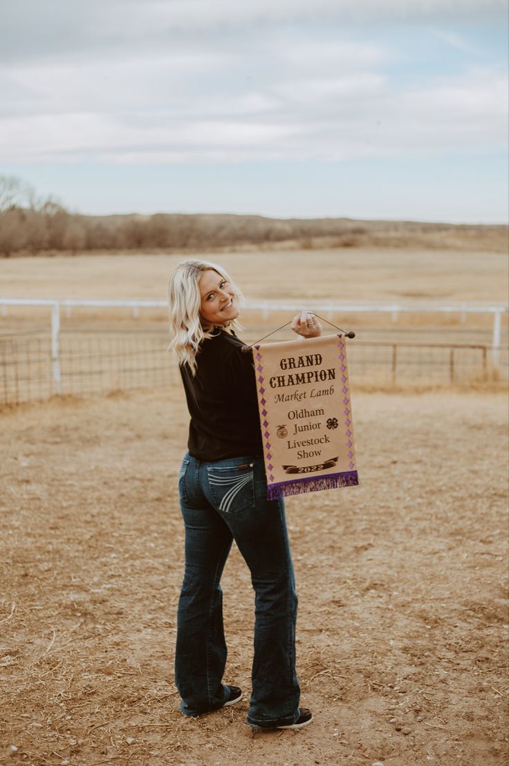 a woman holding a sign in the middle of a field