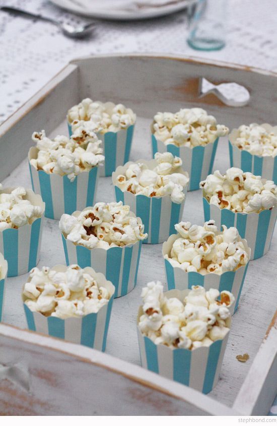 blue and white striped cupcakes with nuts in them on a tray next to silverware