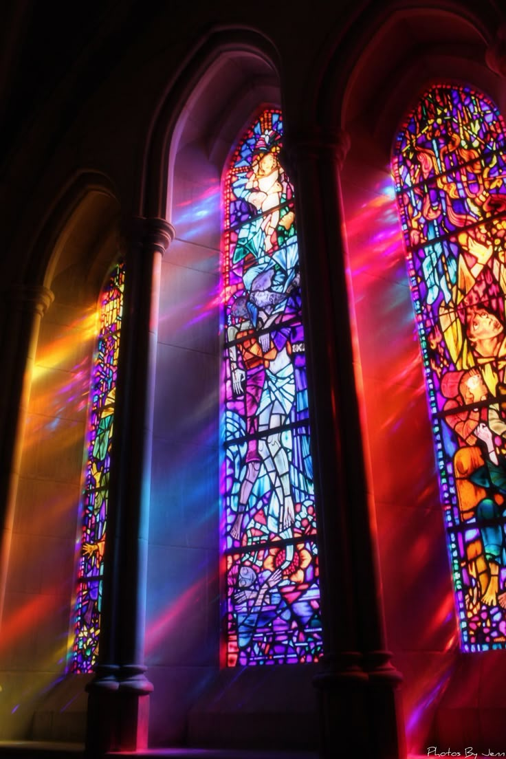 two large stained glass windows sitting next to each other in a building with sunlight streaming through them