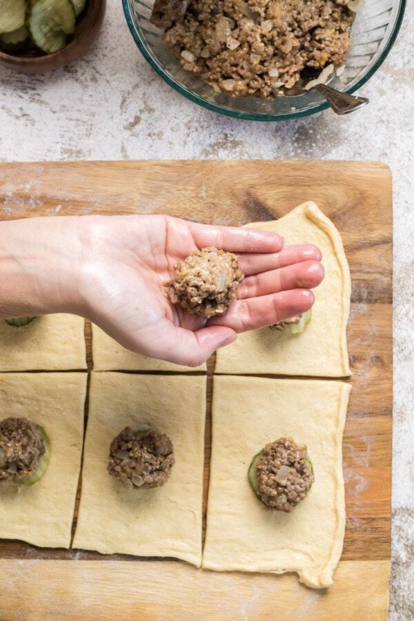 a person holding food in their hand over dough