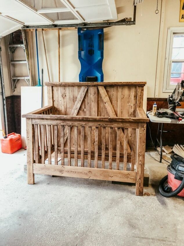 a wooden crib in a garage with tools on the floor