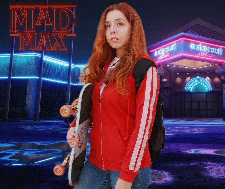 a girl with red hair holding a skateboard in front of a building at night