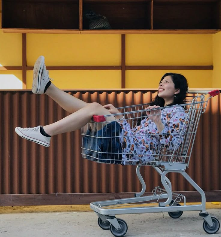 a woman sitting in a shopping cart with her legs crossed and feet up on the handle