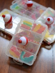 two plastic containers filled with different colored candies on top of a wooden table next to each other