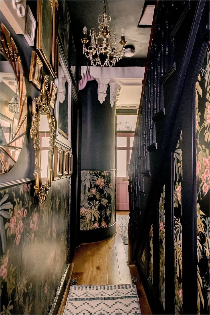 an ornate hallway with floral wallpaper and chandelier