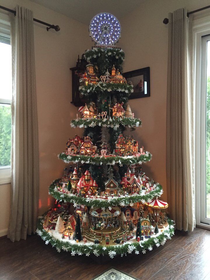 a christmas tree with many ornaments on it in a living room next to two windows