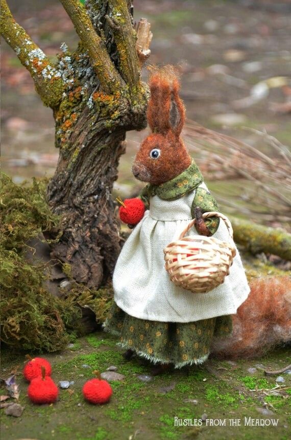 a stuffed squirrel holding a basket next to a tree with red berries on the ground