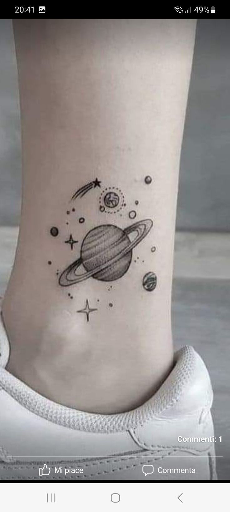 a small saturn tattoo on the ankle with stars and planets around it's neck