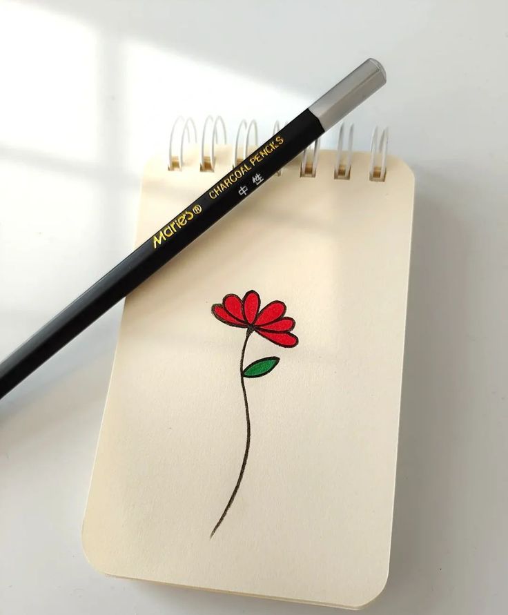 a notepad with a drawing of a flower on it and a black pencil next to it