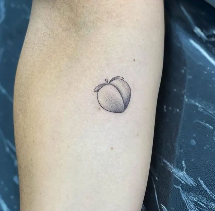 a small apple tattoo on the left inner arm, with an orange in the middle