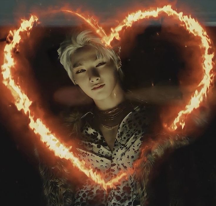 a woman holding a heart shaped object in her hands with flames coming out of it