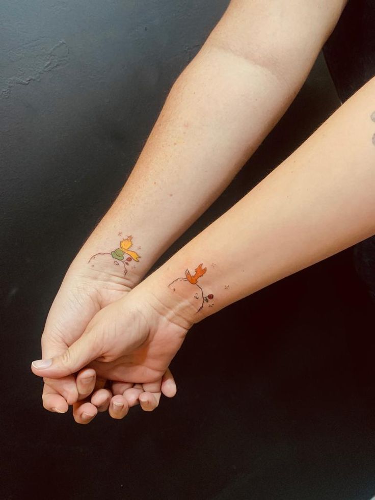 two people holding hands with tattoos on them